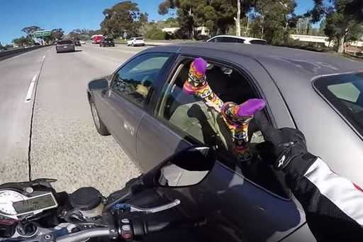 Mischievous motorcyclist gives car passenger a fright in a slightly cheeky way